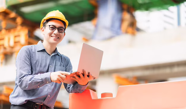 smart-asian-male-professional-civil-engineer-hand-hold-laptop-site-construction-check-with-infastrcture-building-background_609648-1327